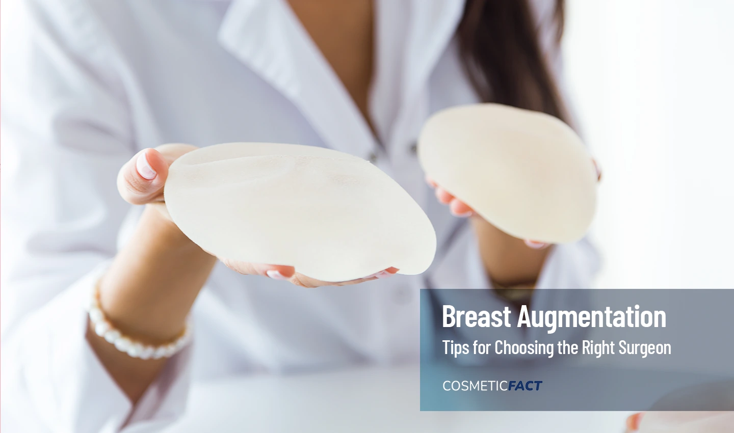 Skilled Breast Augmentation Surgeon holding prosthesis for breast augmentation surgery in a medical setting.