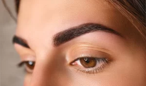 A close-up of a woman's face with perfectly shaped eyebrows, showcasing the results of eyebrow shaping tips for achieving a perfect arch