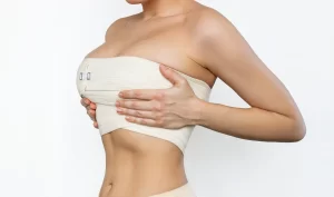 Woman with bandage around her breast during the healing process of breast augmentation recovery.