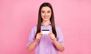 Affordable Cosmetic Dentistry: Smiling woman holding a credit card with noticeably whiter teeth