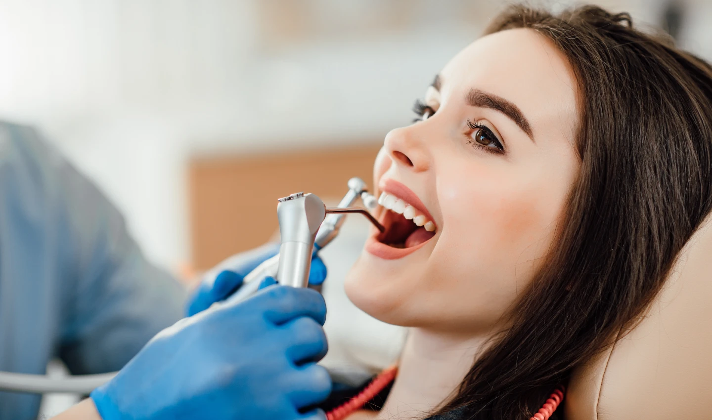 Young woman smiles during teeth beauty surgery performed by a dental surgeon