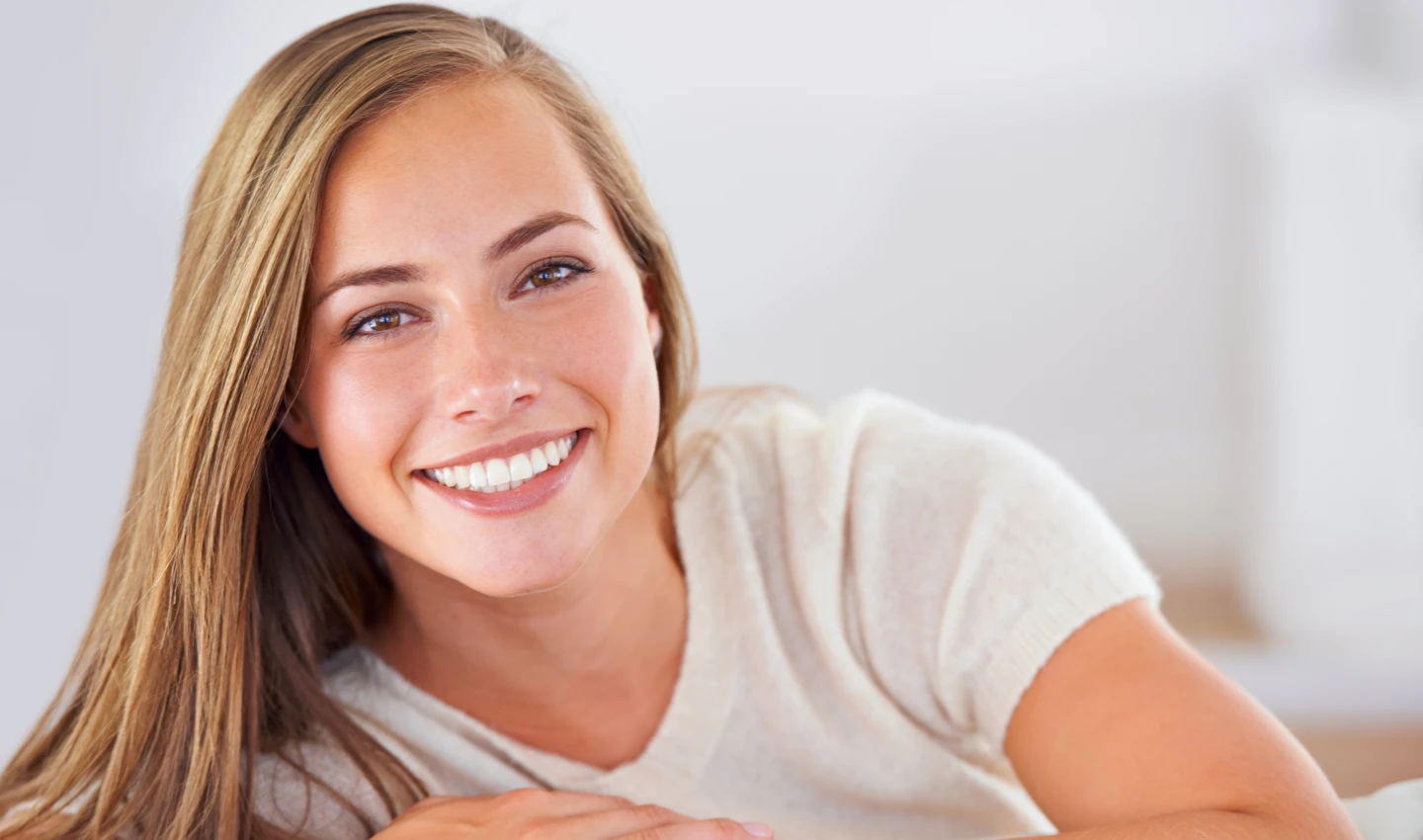 A young woman smiling with perfect teeth after teeth beauty surgery, representing the achievement of managing expectations in cosmetic dental procedures.