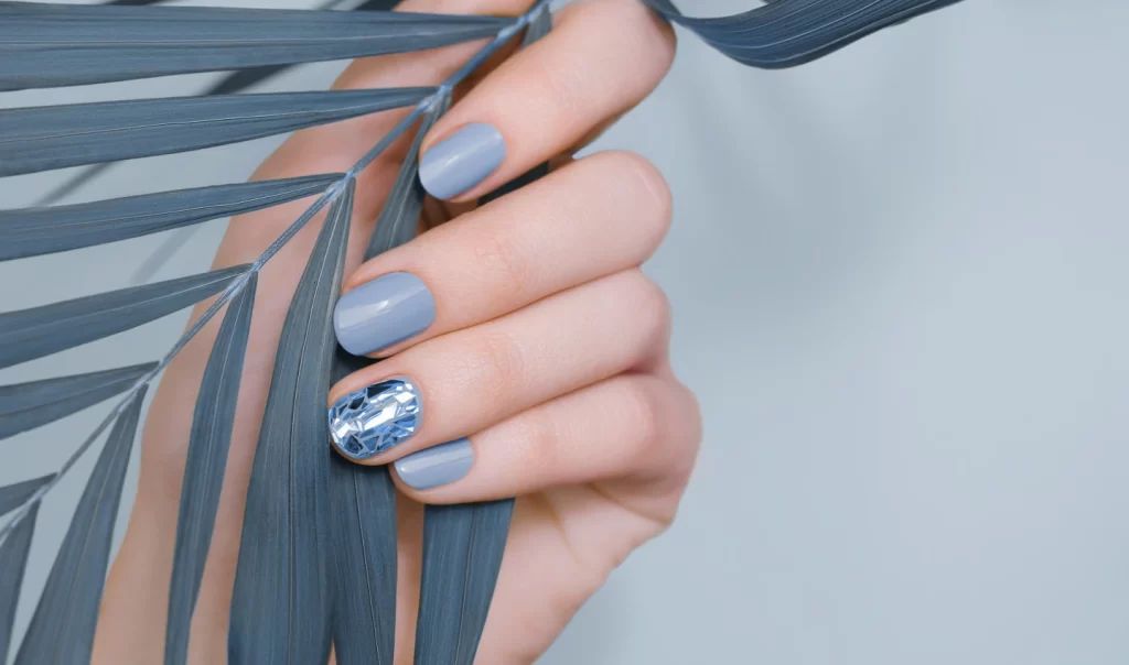 A person holding a nail tool next to their beautiful, creatively designed nails, showcasing Nail Art Designs.