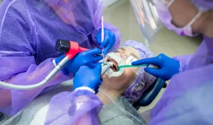 Two dentists performing orthodontic revision surgery on a patient's teeth, showcasing the latest Perfect Smile Techniques in action.