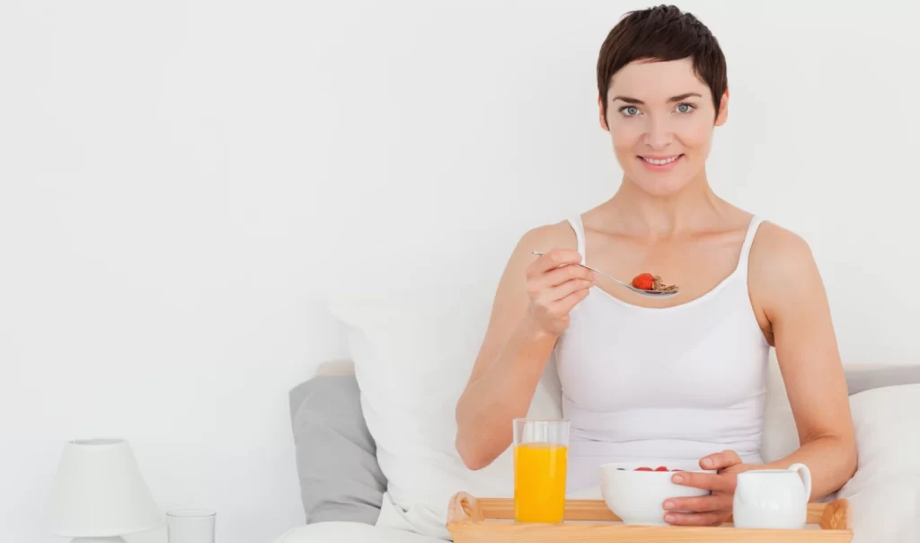 Woman holding a bowl of vitamin C-rich fruits, including oranges, strawberries, and kiwis, emphasizing the importance of vitamin C skincare for achieving brighter, smoother skin.