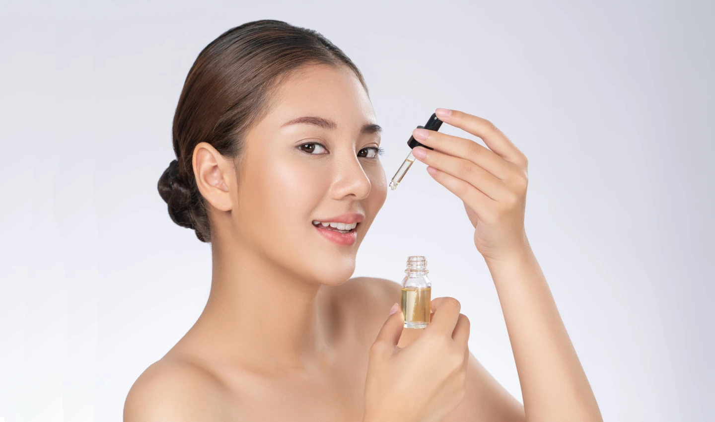 Young woman using Vitamin C Serum on her face for brighter and healthier skin.