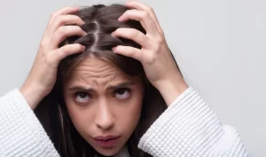 Image of a worried woman touching her loose hair, representing the emotional impact of hair loss and the importance of recovery time after hair loss treatment.