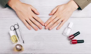 A person's well-manicured nails along with a nail instrument, representing Nail Strengthening Tips for achieving healthy and beautiful nails.