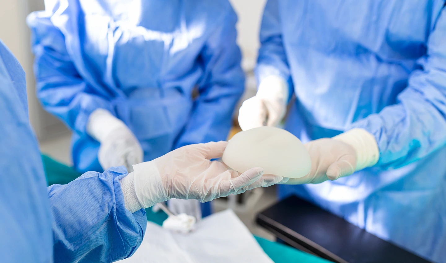 Breast augmentation surgeon receives a prosthesis during surgery, demonstrating the importance of experience and skill in achieving optimal results.