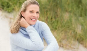 A middle-aged woman with a nice smile after teeth beauty surgery, demonstrating the achievable realistic results of teeth beauty surgery for those with realistic expectations.