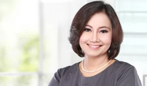 An Oriental middle-aged woman smiling to the camera with straightened and whitened teeth, representing the global phenomenon of teeth beauty surgery.