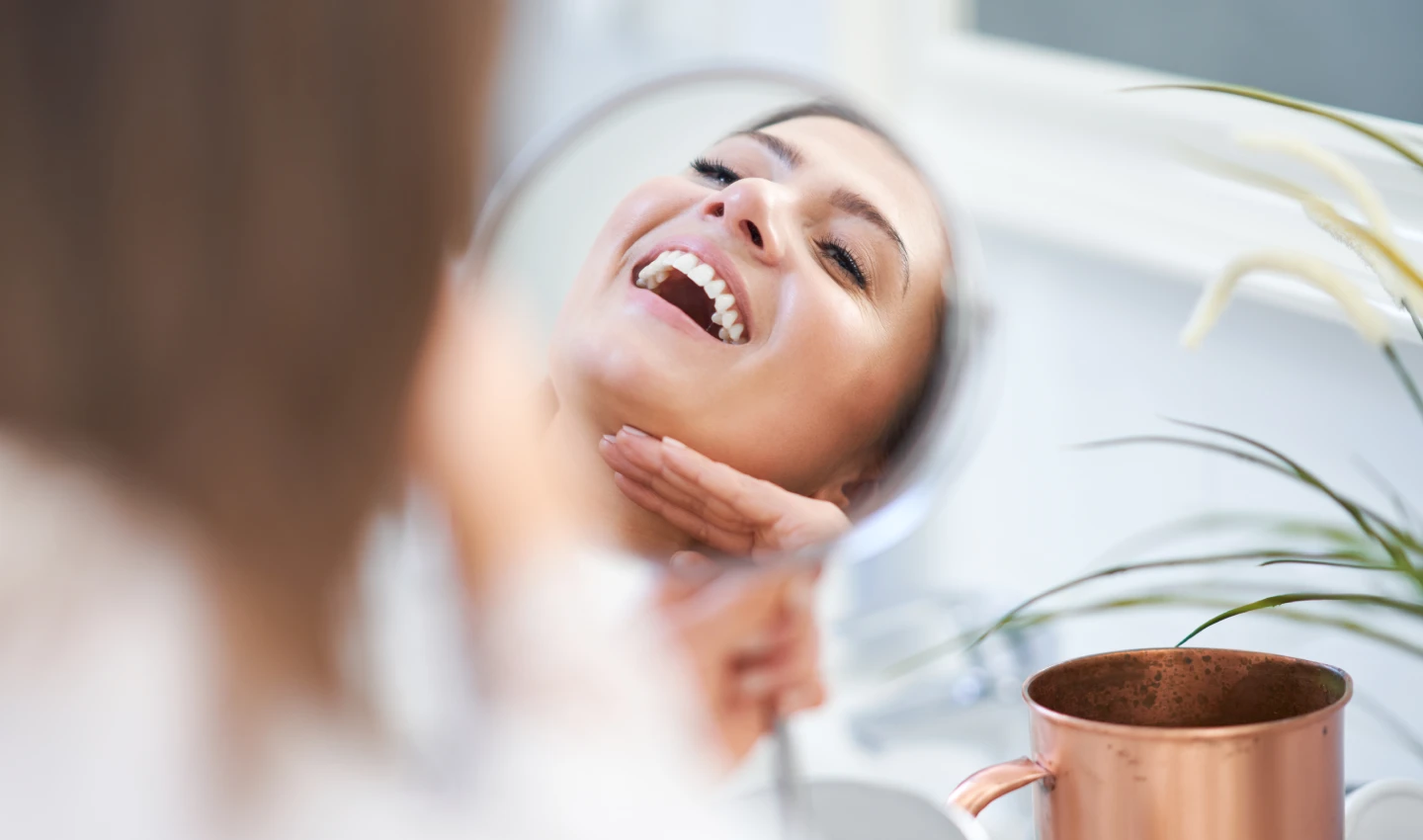 Patient smiling in the mirror after successful dental bonding recovery, showcasing the benefits of cosmetic dentistry for a stress-free and confident smile