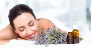 Woman smiling and waiting for an aromatherapy massage surrounded by candles and essential oils.
