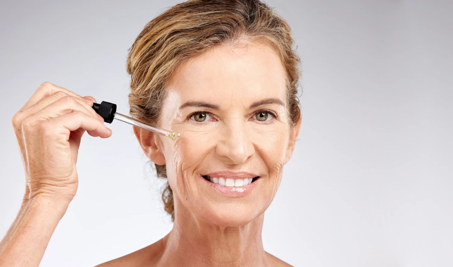 An older woman with visibly softened fine lines and wrinkles on her face after using Retinol Treatments.