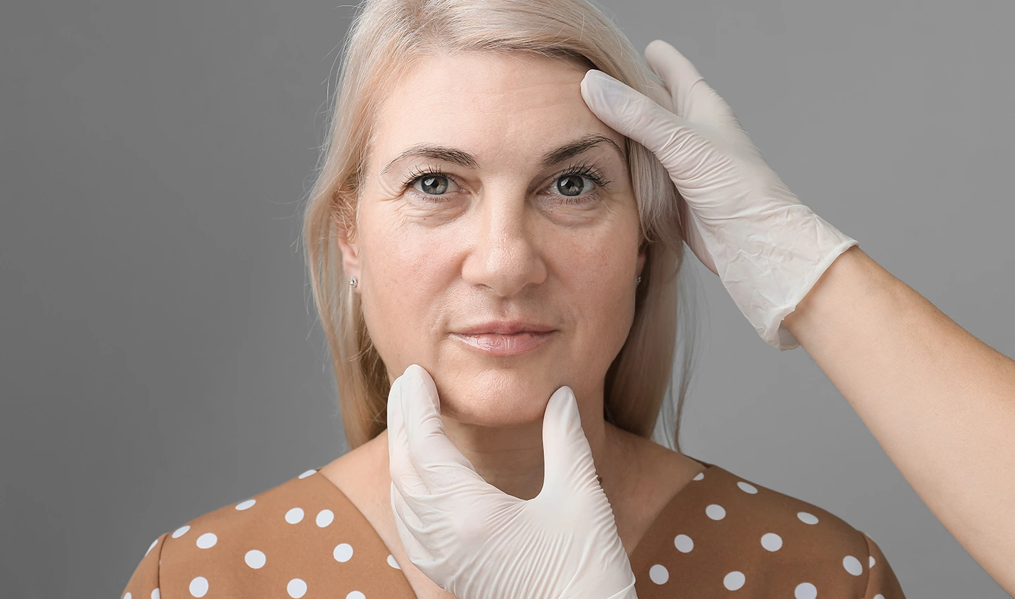 Facelift Surgery Benefits: Image of a mature woman being examined by a plastic surgeon for facelift surgery.