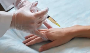 A woman's hands receiving an injection for hand rejuvenation treatment using dermal fillers.
