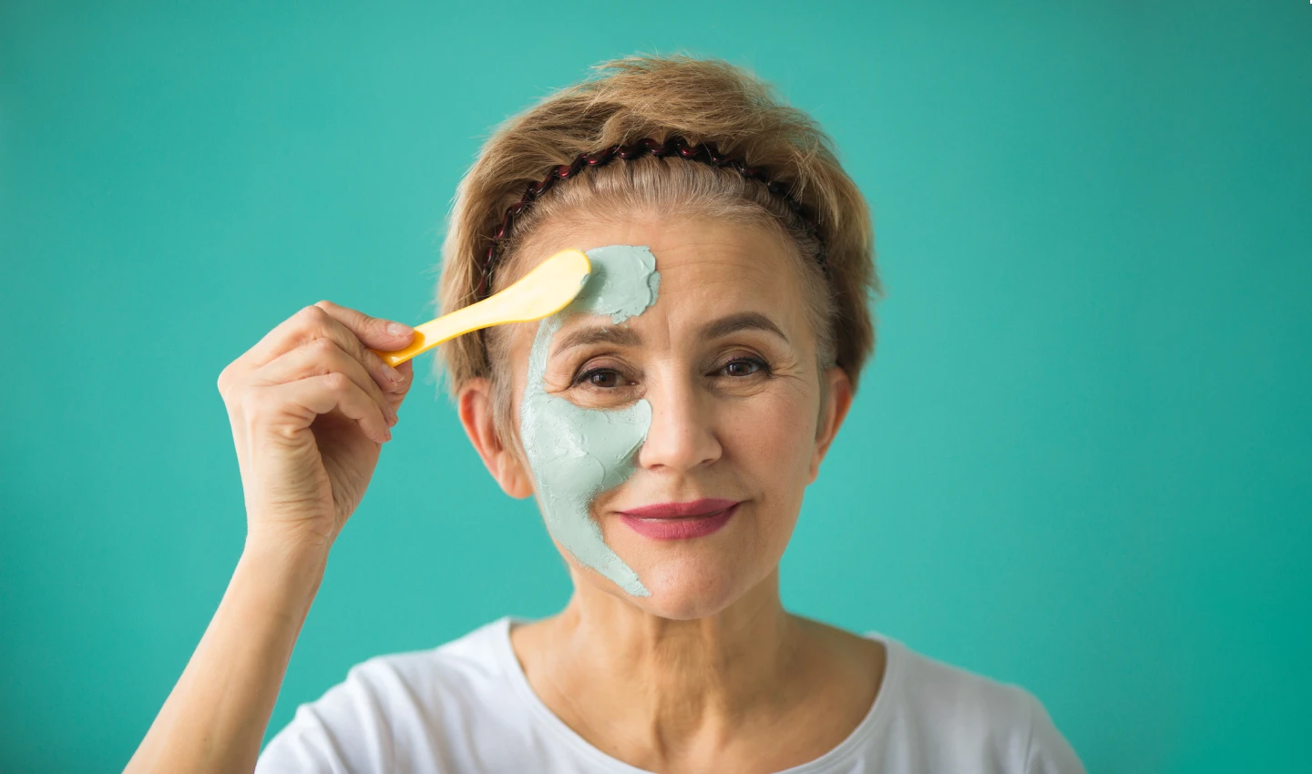 An old woman with hydrated skin applying a hydrating mask. The image showcases the power of hydrating masks for nourished skin.