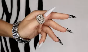 A woman's hand with long, designed nails, showcasing the beauty and versatility of nail extensions