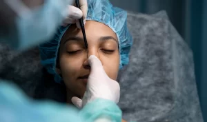 Black woman in a hospital gown preparing for a combined facelift and rhinoplasty surgery to achieve facial harmony.