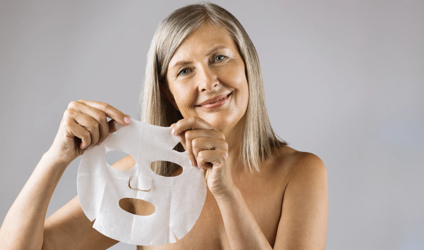 Mature woman using anti-aging face mask, as mentioned in the Anti-Aging Masks Guide.