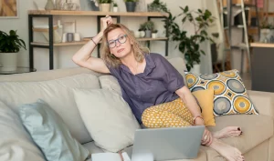 Woman sitting on a sofa, considering Home Preparation Tips for Facelift Surgery