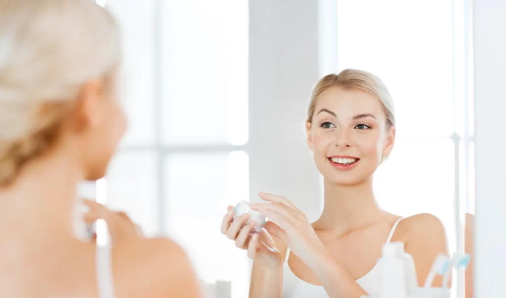 A woman looks at herself in the mirror after exfoliation skincare, showcasing a radiant complexion.