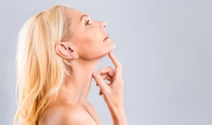 Woman demonstrating the results of jawline contouring with dermal fillers, showcasing a defined jawline.