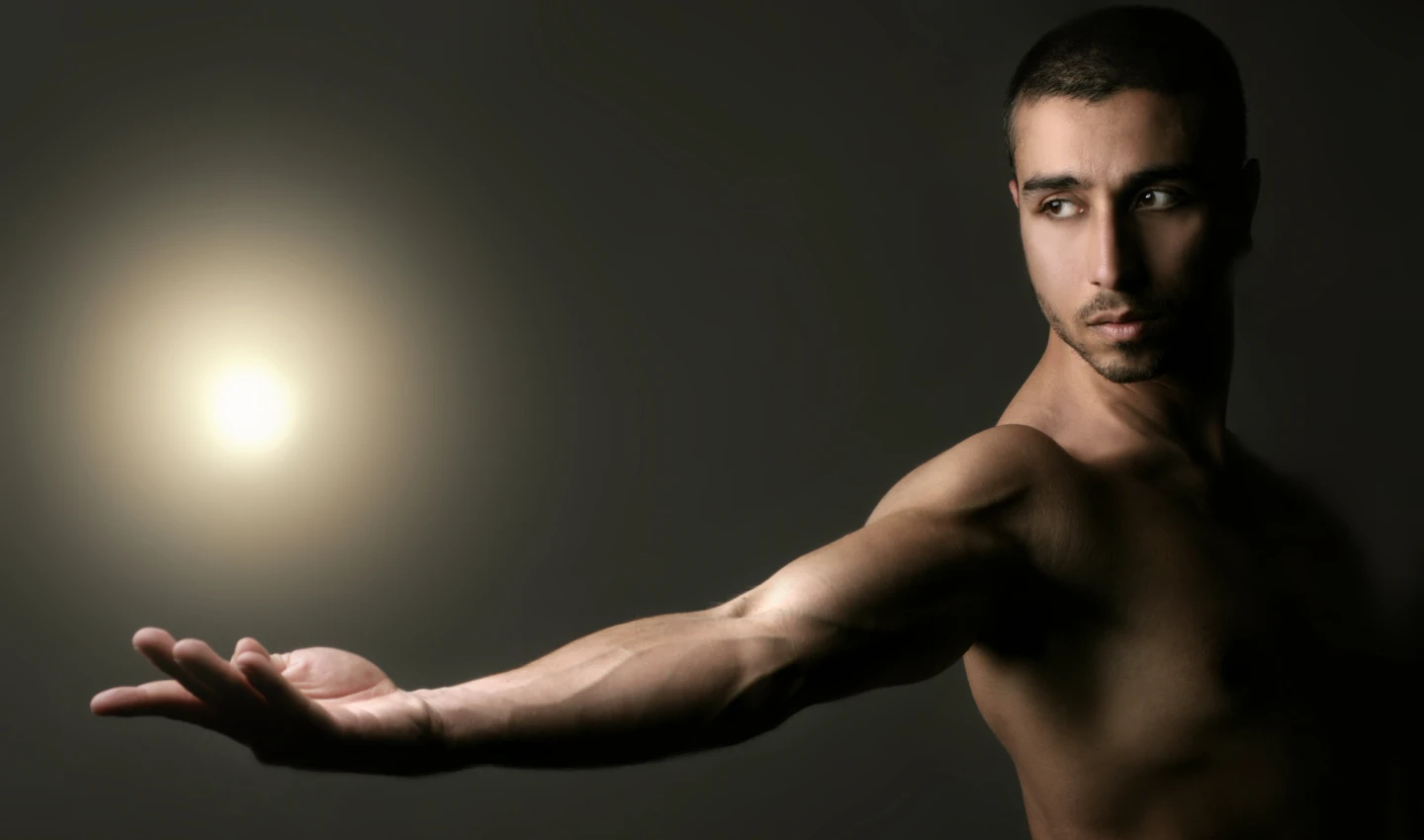 Visualization in Men's Body Care - An image of a muscular arm against a black background with a shiny spot in the background. The well-groomed arm suggests the importance of visualizing your body care routine for achieving desired results.