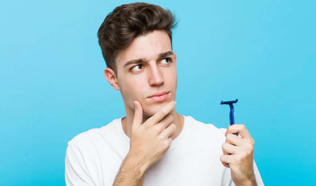 Man holding a shaver and thinking about choosing the right razor for his skin type.