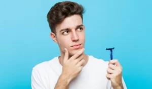 Man holding a shaver and thinking about choosing the right razor for his skin type.