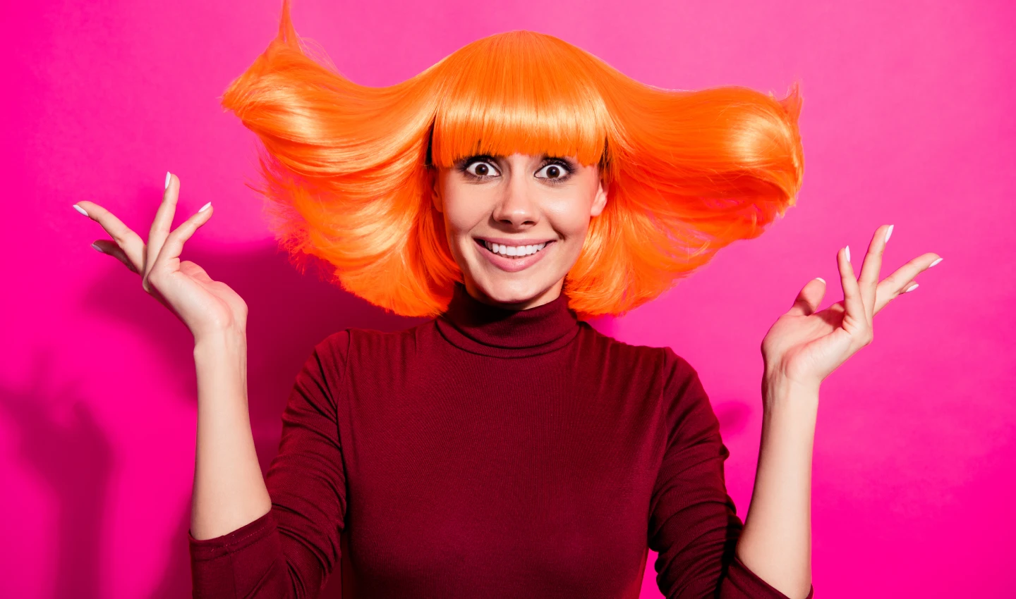 A woman with vibrant orange hair looks happy and confident, showcasing the transformative power of bold hair hues for a striking new look.