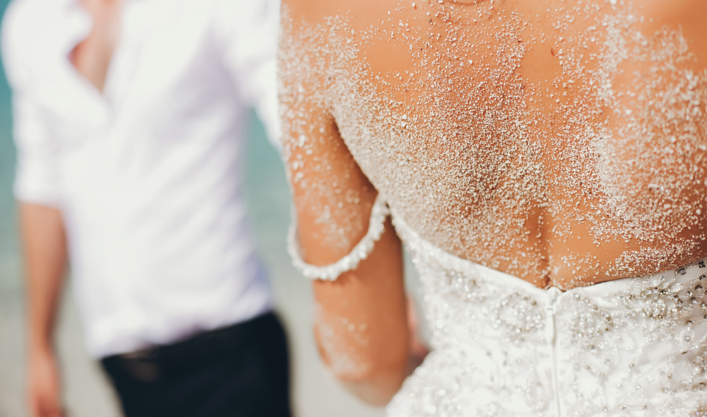 A woman in a white wedding dress with some skin powder on it, after undergoing a pre-wedding body wrap treatment.