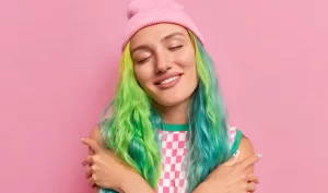 Woman with trendy pastel green hair, looking satisfied.