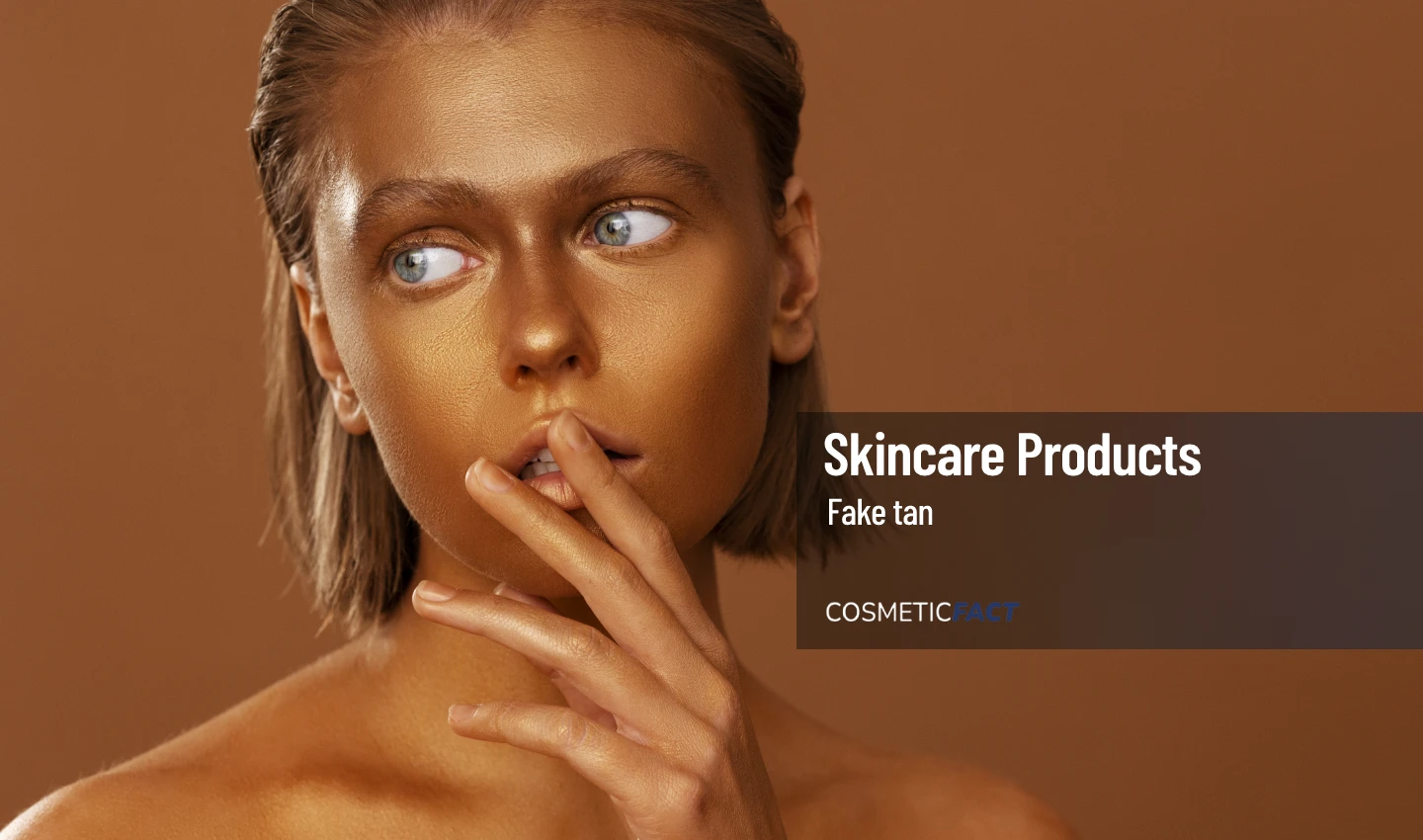 Woman with a tan face holding a bottle of fake tan, representing the skincare benefits of using fake tan.