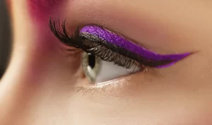 A close-up view of a green eye with shiny bold purple eyeliner, showcasing the impact and creativity of using colored eyeliners to enhance your eyes and create unique makeup looks.