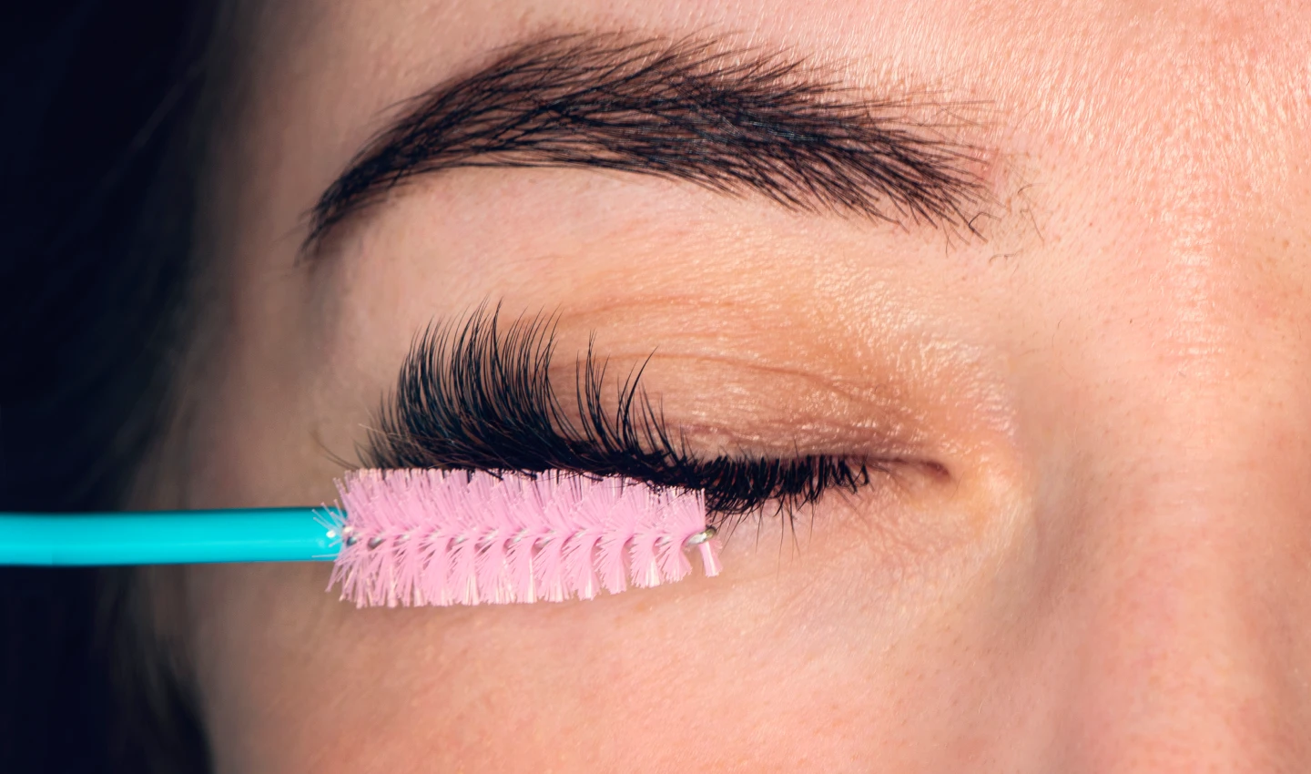 Woman applying mascara while following the tips from the Perfect Mascara Guide.