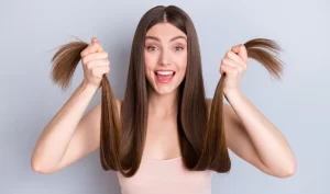 Young woman with extremely long and gorgeous hair laughing at the camera, showcasing the benefits of scalp therapy for promoting healthy hair growth.