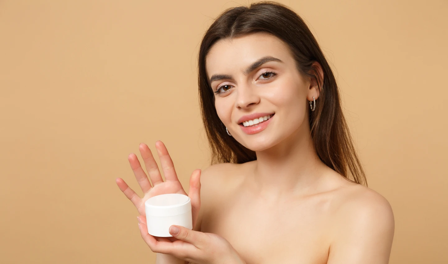 A woman holding a bottle of sunscreen cream, promoting its benefits for nourished and protected skin.