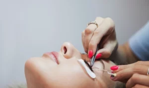 Woman undergoing a lash lift treatment, with eyes closed and lashes being lifted and curled, demonstrating the transformative effects of lash lifts.