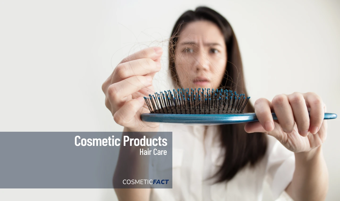 An anxious woman taking out loose strands of hair from a hairbrush, emphasizing the importance of restorative hair treatments for repairing and strengthening damaged hair.