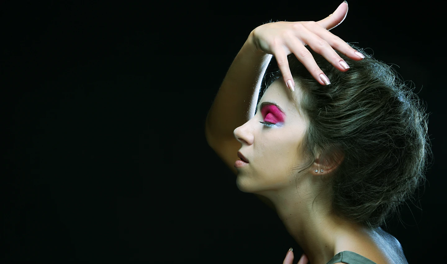 A young woman wearing a bold and artistic eye makeup look featuring a metallic pink eye shadow, showcasing the power of metallic eye shadows in creating unique and captivating makeup looks.