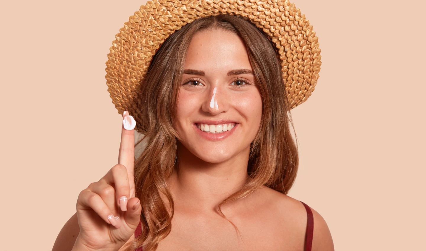 Woman applying sunscreen on her face with a smile, demonstrating the importance of choosing the right sunscreen for your skin type.