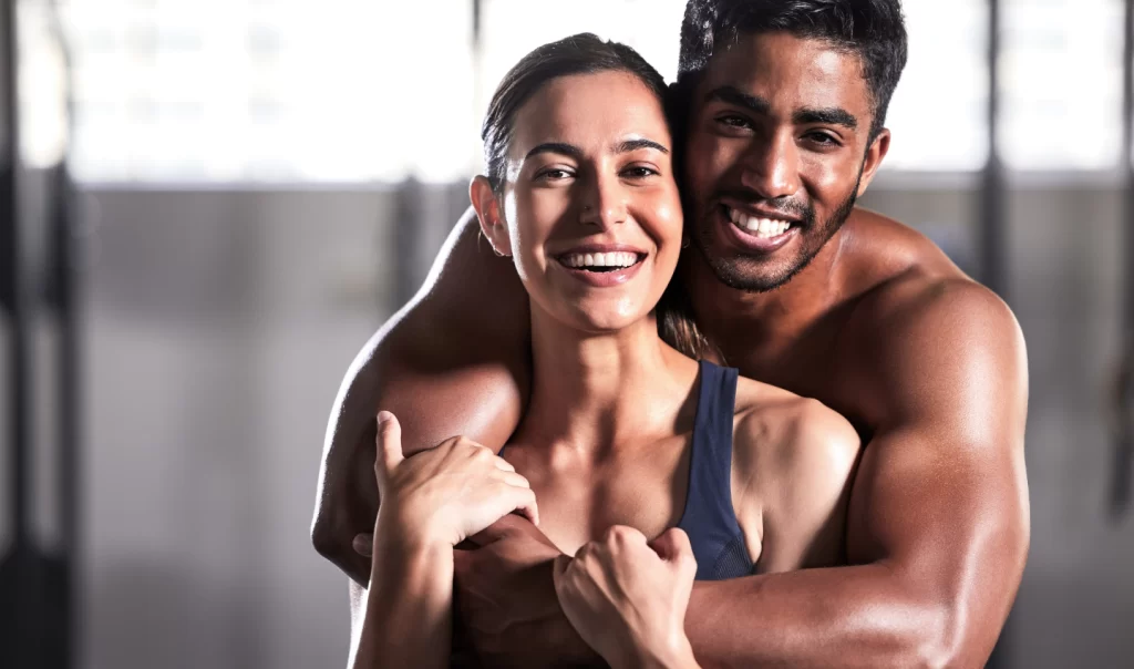 A man and woman standing next to each other, both happy and athletically fit, having undergone laser hair removal for athletes.