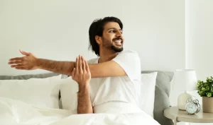 Men's Self-Massage - An image of a young man in comfortable white clothes giving himself a self-massage. The man is using his hands to apply gentle pressure to his neck and shoulders, suggesting the benefits of incorporating self-massage into your body care routine. The image emphasizes the simplicity and accessibility of self-massage, which can be done anywhere, anytime.