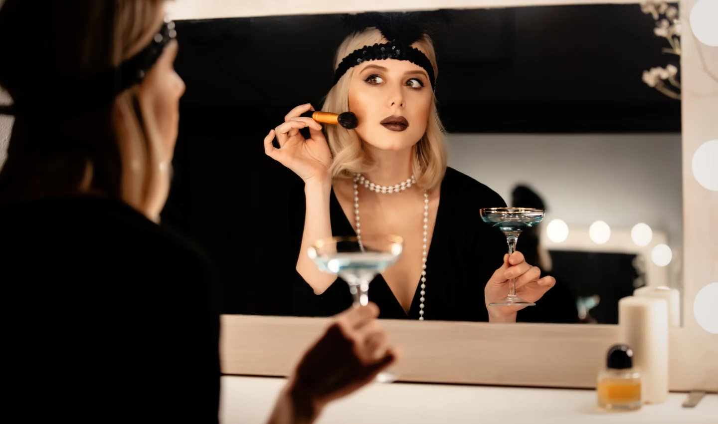 Woman in black dress applying cream blush using essential techniques in front of a mirror.