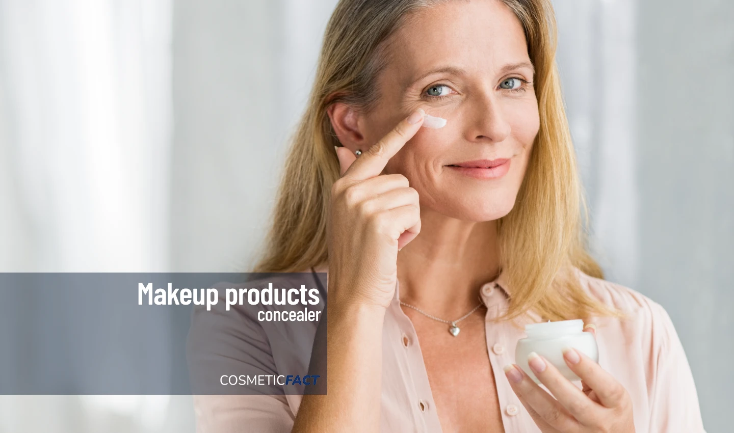 Middle-aged woman applying cream under her eyes for an ageless beauty look, highlighting the importance of choosing the right concealer for mature skin.