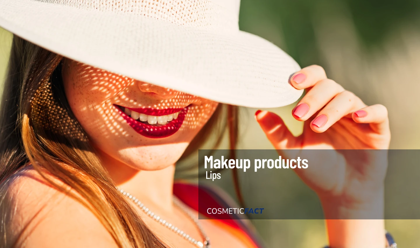 Woman with beautiful lipstick and hat holding a tube of sun-protective lip balm for outdoor adventures.