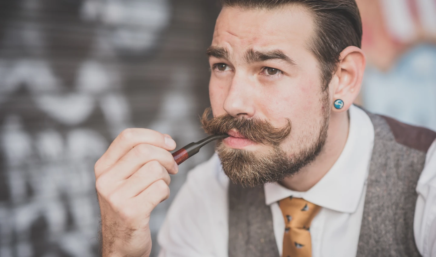 A man with a well-groomed mustache demonstrates proper grooming techniques in this image about mustache grooming tips for men.