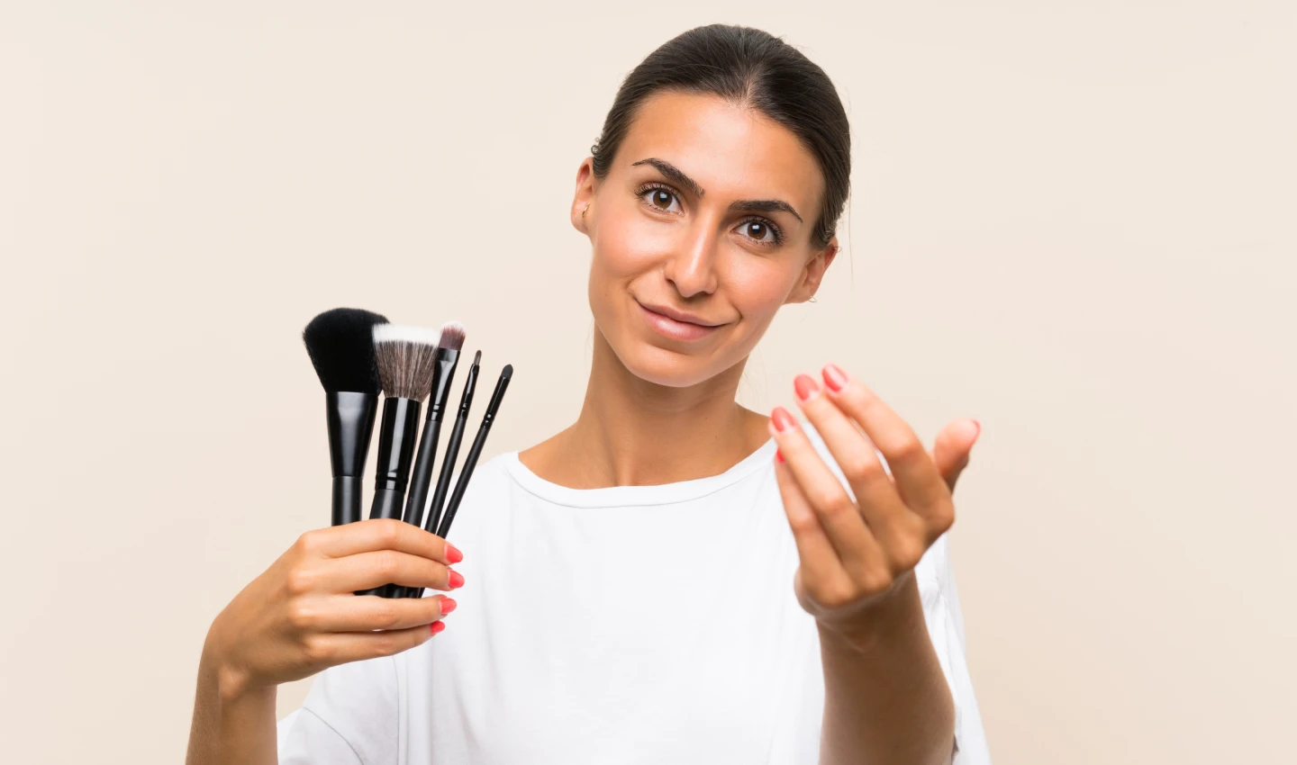 Ideal Foundation Brush - Young Woman Inviting with Hand Full of Makeup Brushes