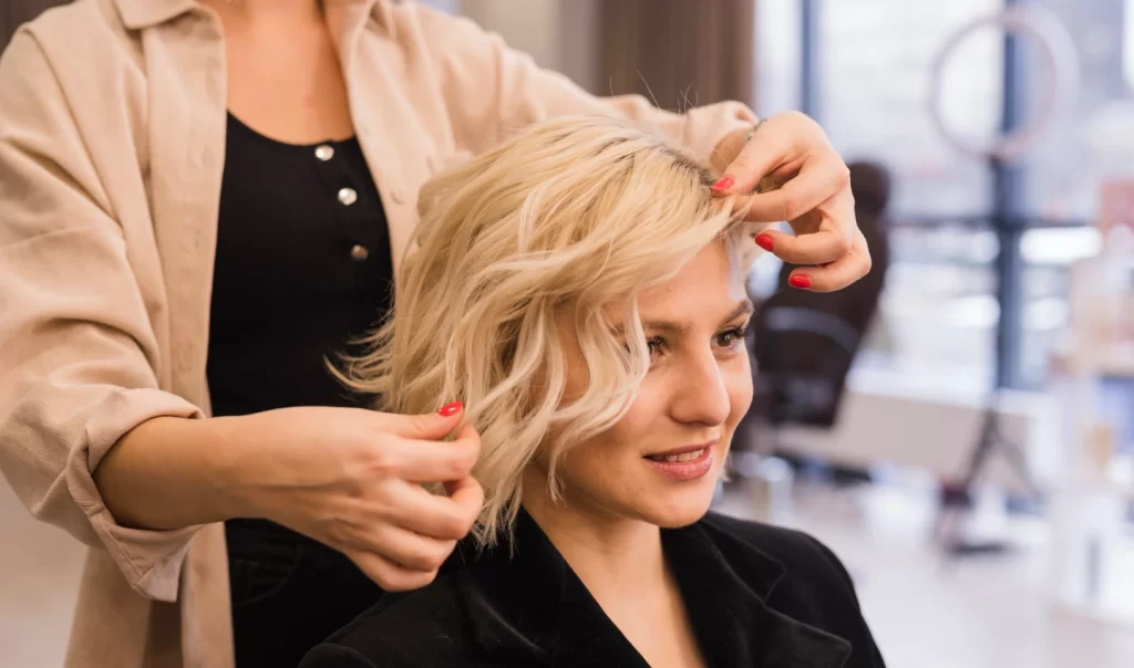 A woman receiving a low-maintenance shag haircut at a barber's chair.